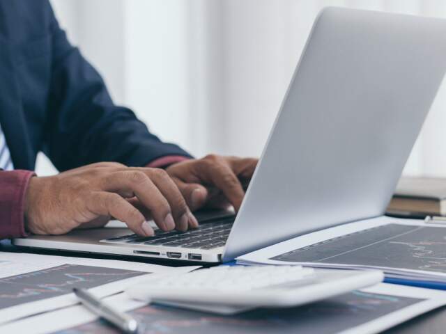 mãos de um homem branco digitando em um notebook