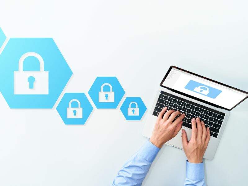 pessoa digitando em um notebook e elementos de cadeados na imagem